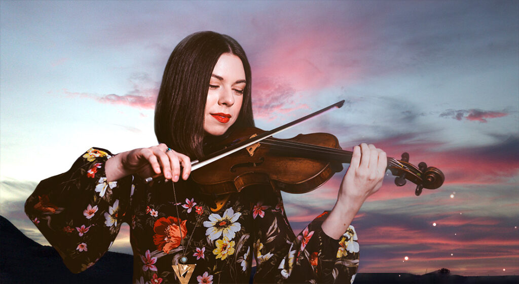 Tessa Lark plays her violin before a sunset of blues and pinks.