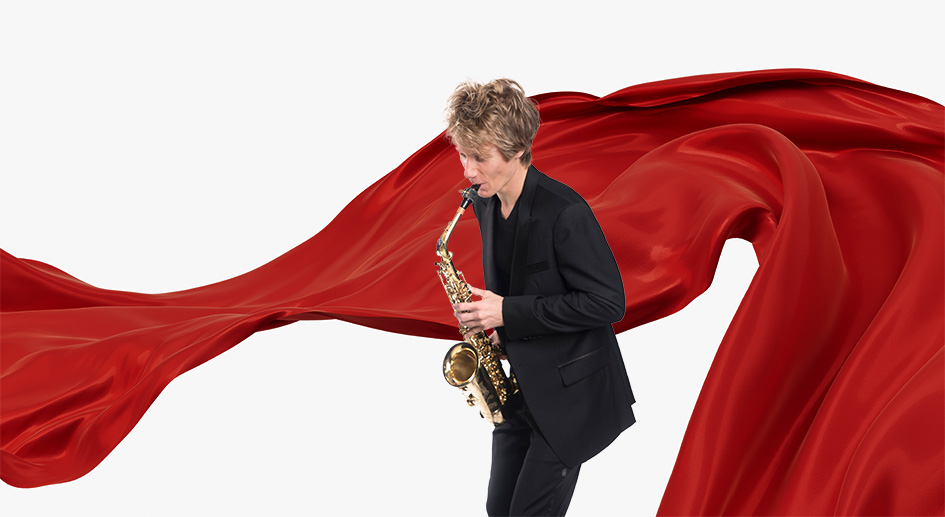 Signature Symphony Artistic Director plays a saxophone in front of a fluttering red banner.